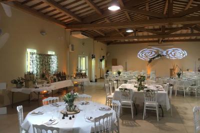 Terrasse extérieure éclairée la nuit, avec des tables et chaises en fer forgé entourées de fleurs colorées.
