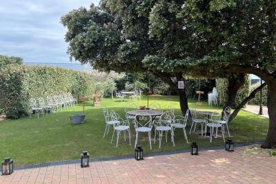 Terrasse extérieure éclairée la nuit, avec des tables et chaises en fer forgé entourées de fleurs colorées.