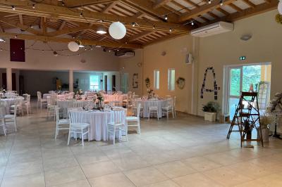 Terrasse extérieure éclairée la nuit, avec des tables et chaises en fer forgé entourées de fleurs colorées.