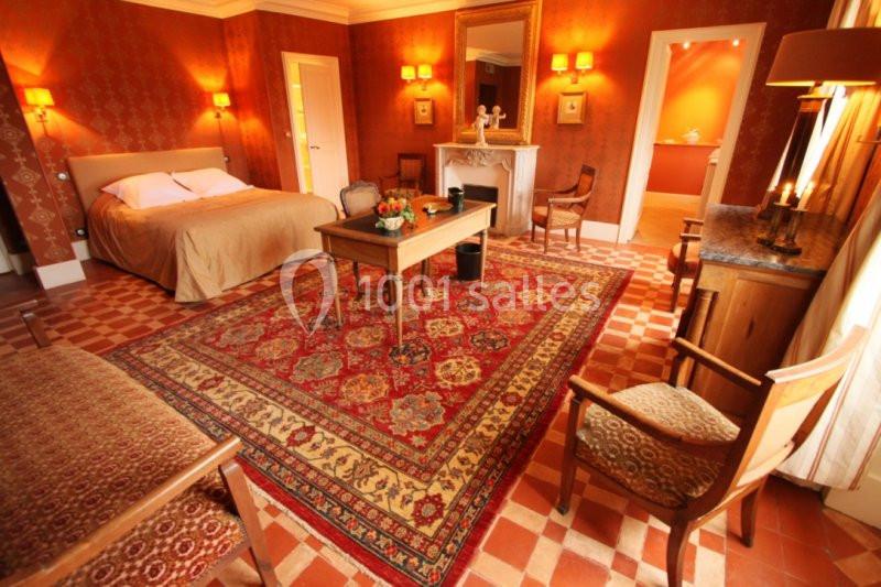 Chambre chaleureuse avec lit double, tapis oriental, mobilier en bois et éclairage doux dans un décor classique.