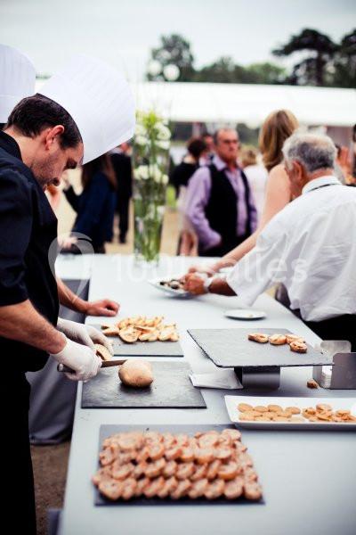 Des chefs préparent et disposent des amuse-bouches sur une table lors d'un événement en plein air.