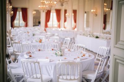 Salle de conférence élégante avec rangées de chaises blanches, lustres suspendus et écran de projection à l'arrière.