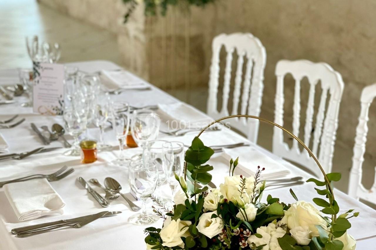 Table de réception élégamment dressée avec une décoration florale composée de roses blanches et de feuillages.