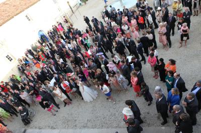 Miniature Location salle Granzay-Gript (Deux-Sèvres) - Château La Bone #33 Un couple de mariés s'embrasse devant une voiture ancienne stationnée dans une cour ensoleillée.