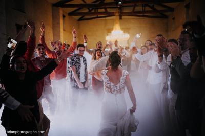 Miniature Location salle Granzay-Gript (Deux-Sèvres) - Château La Bone #5 Un couple de mariés s'embrasse devant une voiture ancienne stationnée dans une cour ensoleillée.