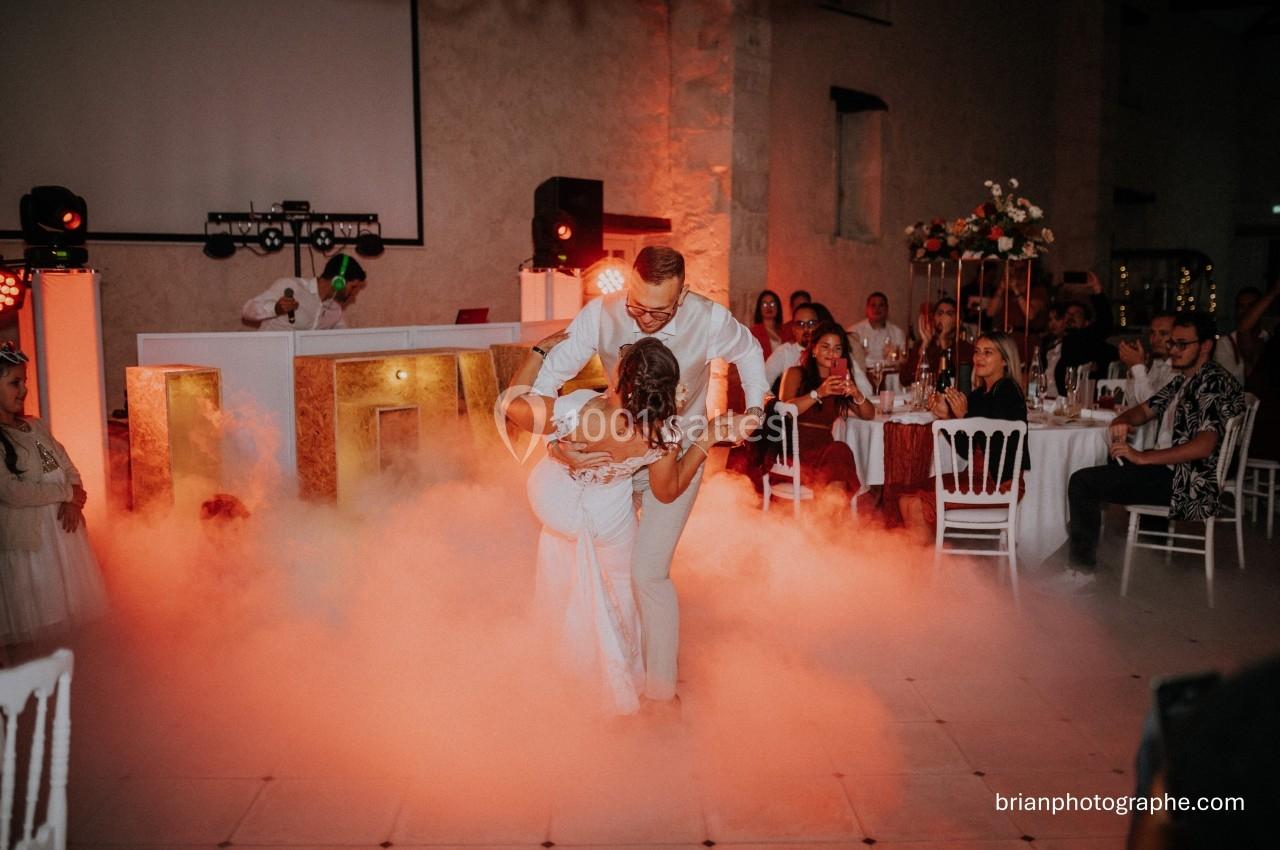 Un couple danse au milieu d'une piste entourée de fumée, sous le regard des invités assis.