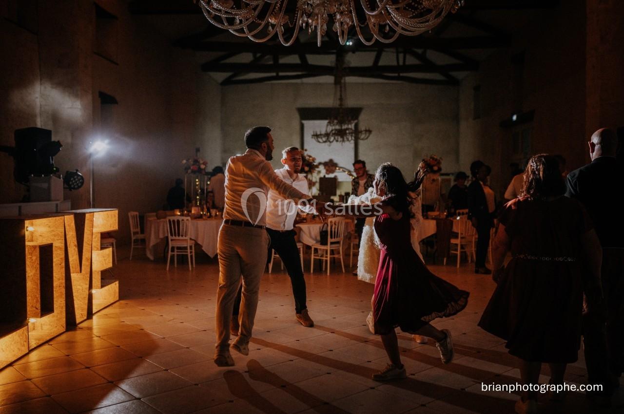 Des personnes dansent dans une salle faiblement éclairée avec un grand panneau lumineux ’LOVE’ en arrière-plan.