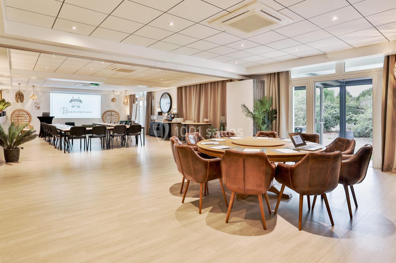 Salle de réunion lumineuse avec tables en bois, chaises en cuir, écran de présentation et grandes baies vitrées donnant sur…