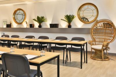 Salle de restaurant lumineuse avec mobilier élégant, banquettes vertes, tables en bois et bar moderne.