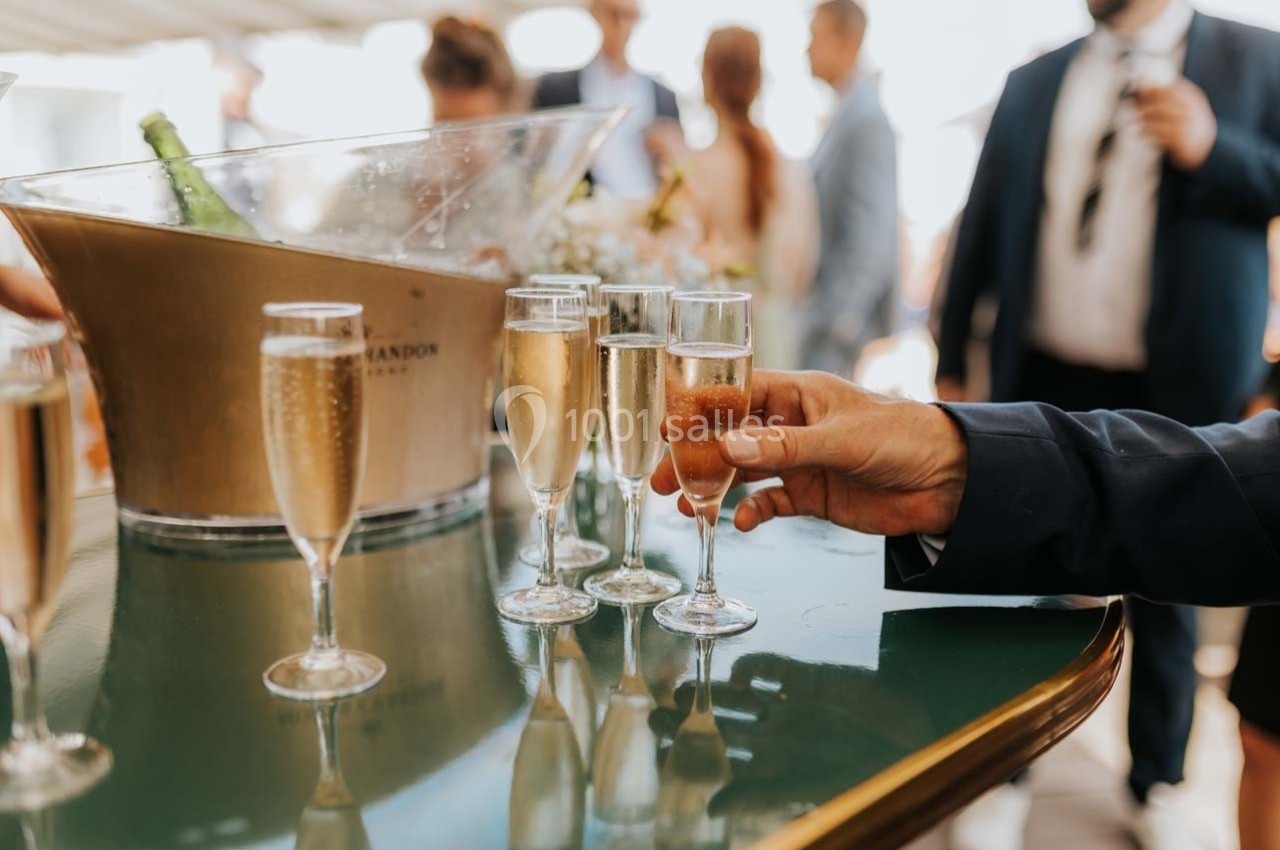 Location salle Talmont-Saint-Hilaire (Vendée) - Bourgenay Golf Club #13 Un homme en costume prend une flûte de champagne sur une table avec d'autres verres et un seau à champagne en arrière-plan.