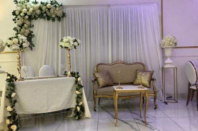 Salle décorée avec des tables rondes dressées, nappes blanches, chaises élégantes et centre de table floral.
