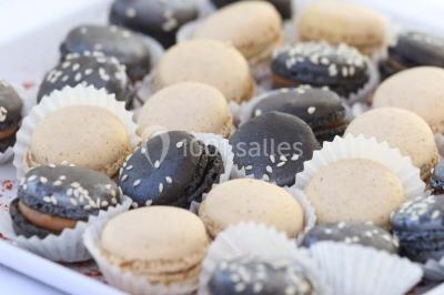Allée gravillonnée bordée de verdure et de plantes, menant à une entrée avec des arches blanches sous un ciel dégagé.