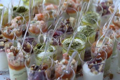 Allée gravillonnée bordée de verdure et de plantes, menant à une entrée avec des arches blanches sous un ciel dégagé.