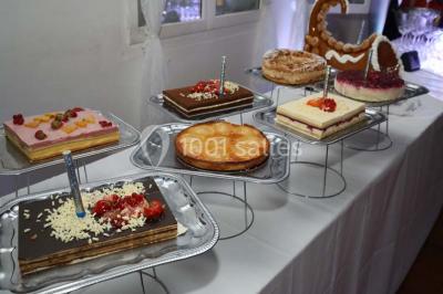 Allée gravillonnée bordée de verdure et de plantes, menant à une entrée avec des arches blanches sous un ciel dégagé.