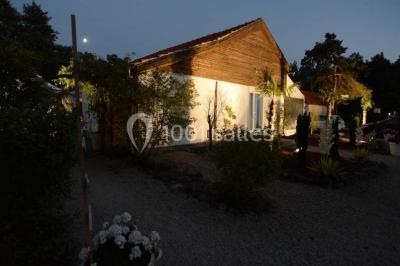 Allée gravillonnée bordée de verdure et de plantes, menant à une entrée avec des arches blanches sous un ciel dégagé.