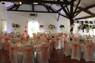 Allée gravillonnée bordée de verdure et de plantes, menant à une entrée avec des arches blanches sous un ciel dégagé.