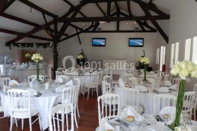 Allée gravillonnée bordée de verdure et de plantes, menant à une entrée avec des arches blanches sous un ciel dégagé.