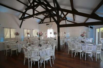 Allée gravillonnée bordée de verdure et de plantes, menant à une entrée avec des arches blanches sous un ciel dégagé.