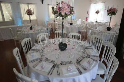 Allée gravillonnée bordée de verdure et de plantes, menant à une entrée avec des arches blanches sous un ciel dégagé.