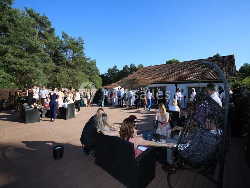 Groupe de personnes réunies sur une terrasse ensoleillée entourée de végétation, discutant et se relaxant.