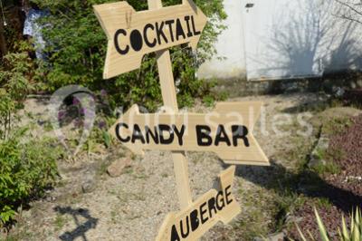 Allée gravillonnée bordée de verdure et de plantes, menant à une entrée avec des arches blanches sous un ciel dégagé.