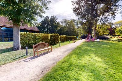 Salle lumineuse avec charpente en bois, tables rondes et chaises, équipée d'un écran de projection.