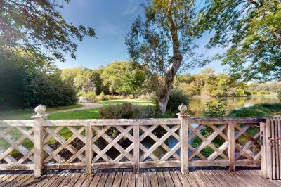 Salle lumineuse avec charpente en bois, tables rondes et chaises, équipée d'un écran de projection.