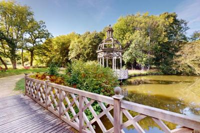 Salle lumineuse avec charpente en bois, tables rondes et chaises, équipée d'un écran de projection.