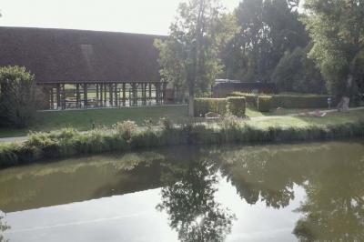 Salle lumineuse avec charpente en bois, tables rondes et chaises, équipée d'un écran de projection.