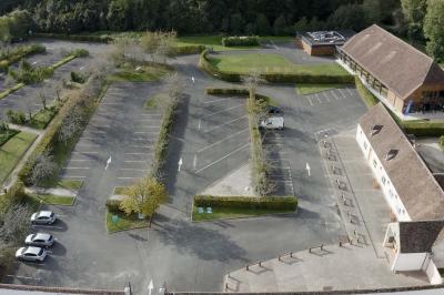 Salle lumineuse avec charpente en bois, tables rondes et chaises, équipée d'un écran de projection.