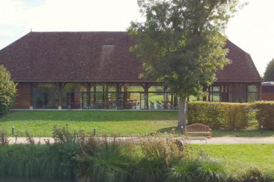 Salle lumineuse avec charpente en bois, tables rondes et chaises, équipée d'un écran de projection.