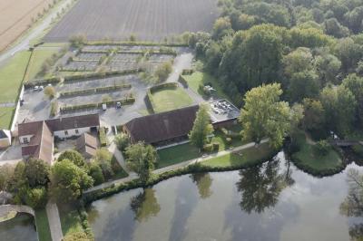 Salle lumineuse avec charpente en bois, tables rondes et chaises, équipée d'un écran de projection.