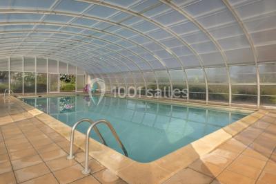 Des animatrices en jupes hawaïennes dansent devant un groupe d'enfants et d'adultes près d'une piscine extérieure.