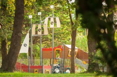 Des animatrices en jupes hawaïennes dansent devant un groupe d'enfants et d'adultes près d'une piscine extérieure.