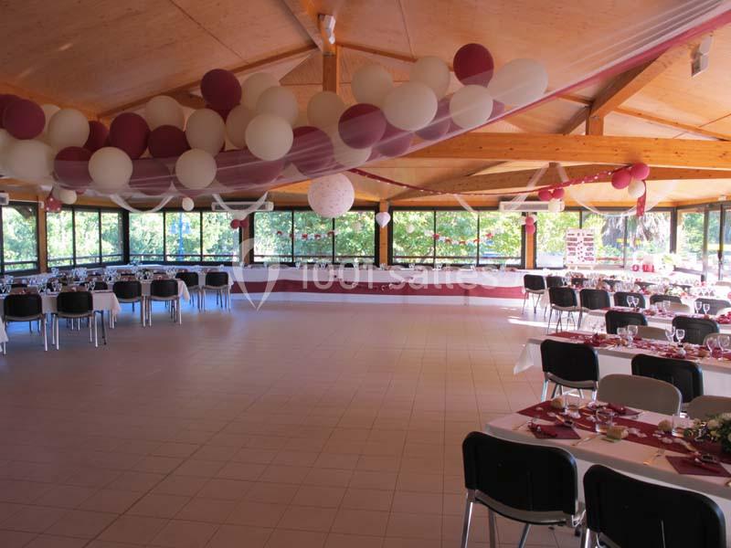 Salle de réception décorée avec des ballons rouges et blancs, tables dressées pour un événement festif.