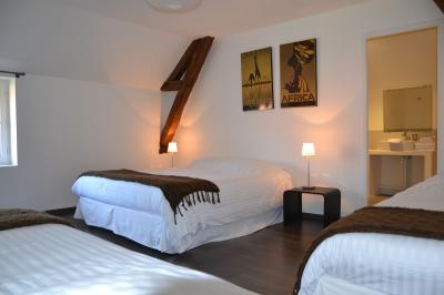 Chambre avec un lit double, un lit simple, deux lampes de chevet allumées et une fenêtre avec rideaux gris.