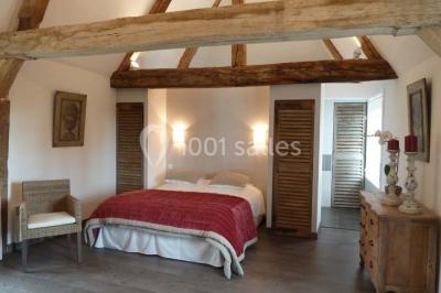 Chambre avec un lit double, un lit simple, deux lampes de chevet allumées et une fenêtre avec rideaux gris.