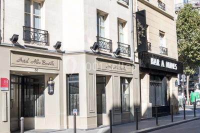 Chambre lumineuse avec un lit double, des murs clairs, des rideaux à rayures et des appliques murales allumées.