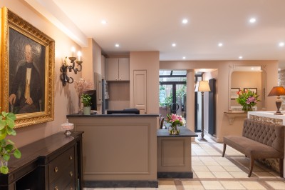 Chambre lumineuse avec un lit double, des murs clairs, des rideaux à rayures et des appliques murales allumées.