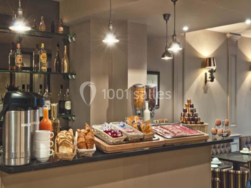 Buffet de petit-déjeuner avec viennoiseries, céréales, jus de fruits et boissons chaudes dans un espace lumineux.