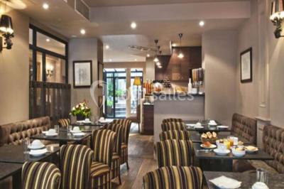 Chambre lumineuse avec un lit double, des murs clairs, des rideaux à rayures et des appliques murales allumées.