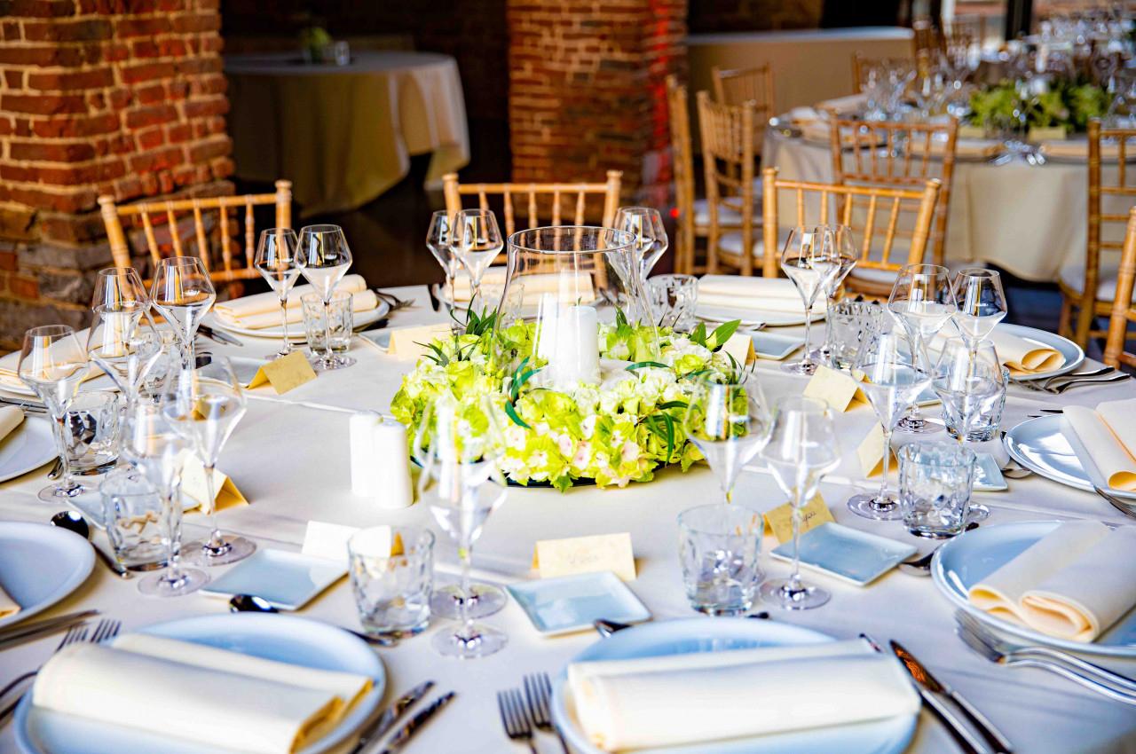 Table élégamment dressée avec nappes blanches, centre de table floral et verres disposés pour un événement formel.
