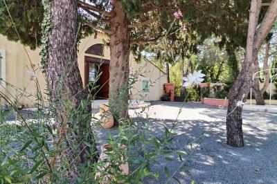 Vue aérienne d'une maison avec toit en tuiles, piscine rectangulaire et jardin arboré dans un cadre rural.