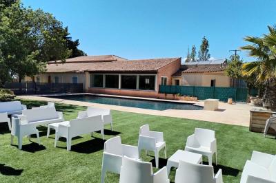 Vue aérienne d'une maison avec toit en tuiles, piscine rectangulaire et jardin arboré dans un cadre rural.