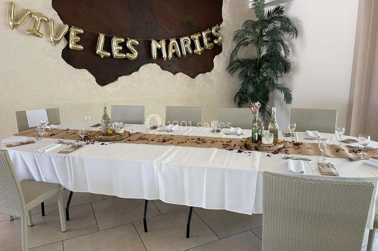 Table décorée pour un mariage avec nappes blanches, pétales rouges, bougies et une bannière ’Vive les mariés’.