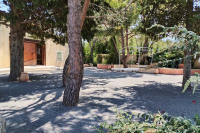 Vue aérienne d'une maison avec toit en tuiles, piscine rectangulaire et jardin arboré dans un cadre rural.