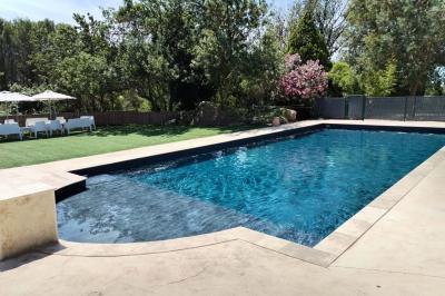 Vue aérienne d'une maison avec toit en tuiles, piscine rectangulaire et jardin arboré dans un cadre rural.