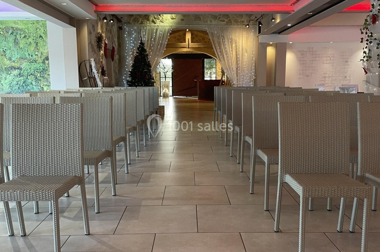 Salle aménagée avec des chaises en rotin alignées, éclairage tamisé et décorations festives en arrière-plan.