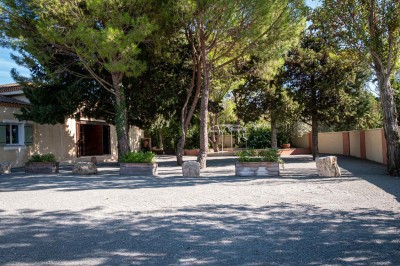Vue aérienne d'une maison avec toit en tuiles, piscine rectangulaire et jardin arboré dans un cadre rural.