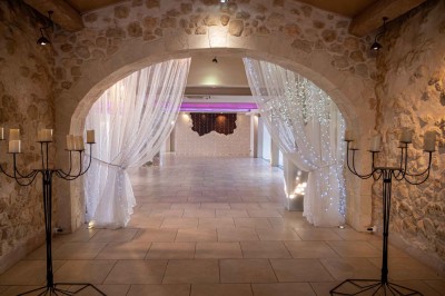 Vue aérienne d'une maison avec toit en tuiles, piscine rectangulaire et jardin arboré dans un cadre rural.